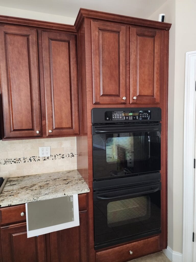 Sherwin Williams Anonymous with cream beige gold granite countertop, travertine tile backsplash, red cherry wood cabinets, samplize peel and stick