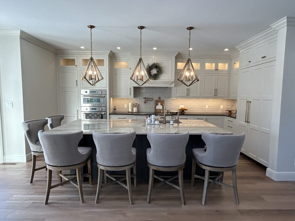Sherwin Williams Pearly White painted kitchen cabinets, wood floor, quartzite countertop, Benjamin Moore French Beret, dark blue island