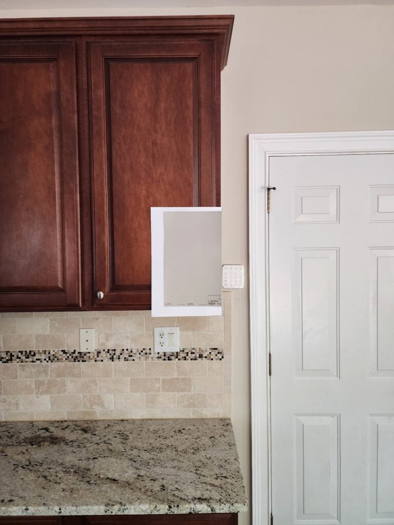Sherwin Williams Versatile Gray samplize peel and stick with travertine tile backsplash and granite couintertop with beige tones, 25 lighter Edgecomb Gray paint on walls