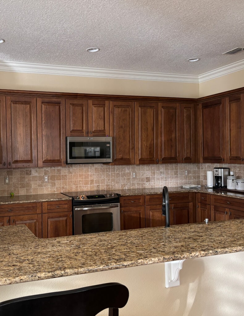 dark oak stained wood kitchen cabinets, granite countertop, travertine tile backsplash, Giallo Ornamental or Venetian Gold