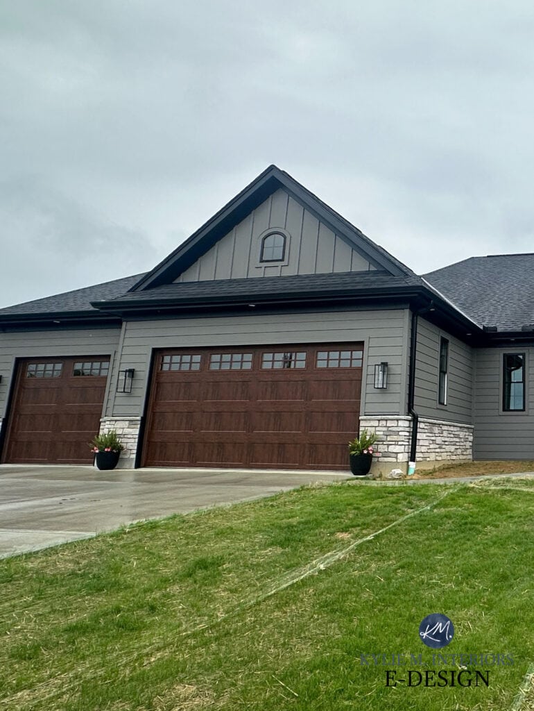 exterior siding painted Sherwin Williams Gauntlet Gray, dark warm gray, fake wood look garage doors, dark wood beams and front door, black asphlat roof, black windows, gutters, exterior stone (1)