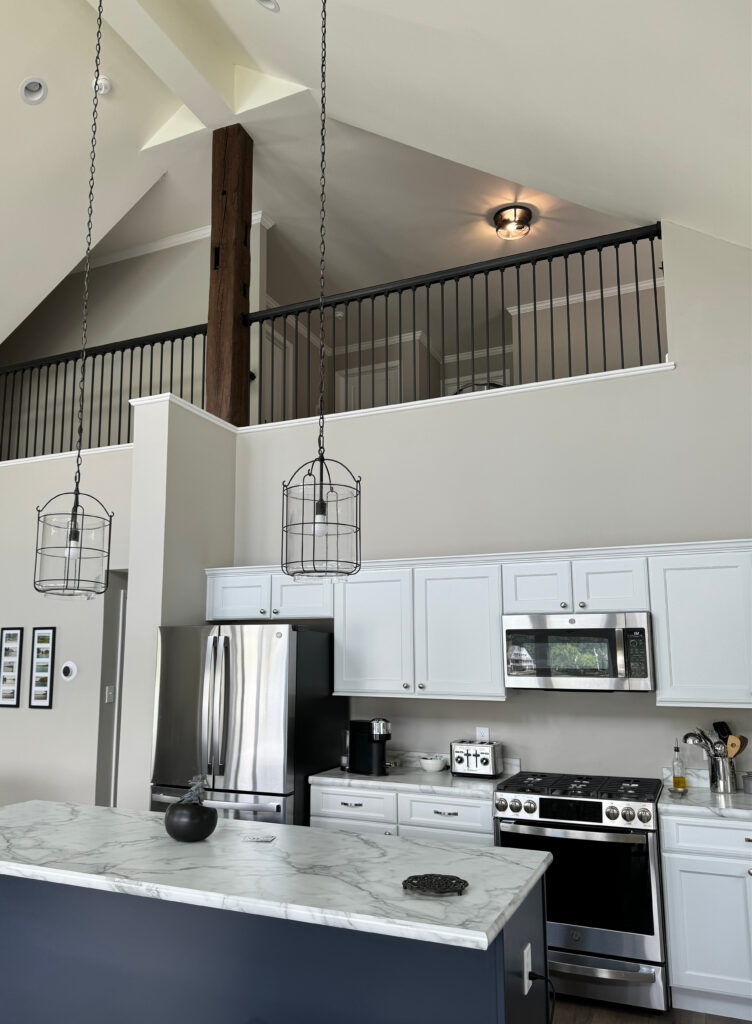 Sherwin Williams Colonnade Gray, white cabinets, formica marble look laminate countertops, Calcatta, stainless hardware, black stair railin with loft, graywash wood flooring, navy blue island