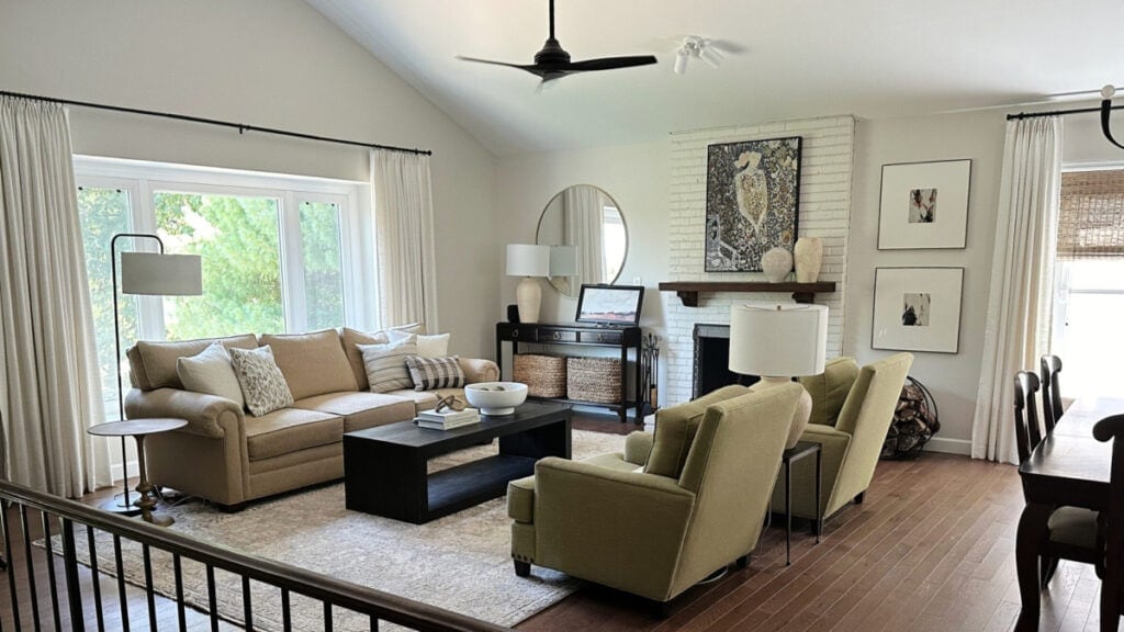 Sherwin Williams White Duck in a living room on a painted brick fireplace and walls, oak floor and green accent chairs with beige sofa