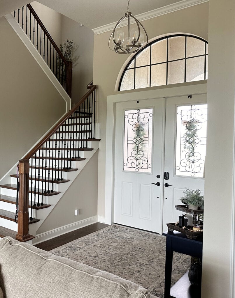Open concept entryway, stairs, Sherwin Williams Accessible Beige, Alabaster trim and doors, wood stairs, white risers, dark wood floor