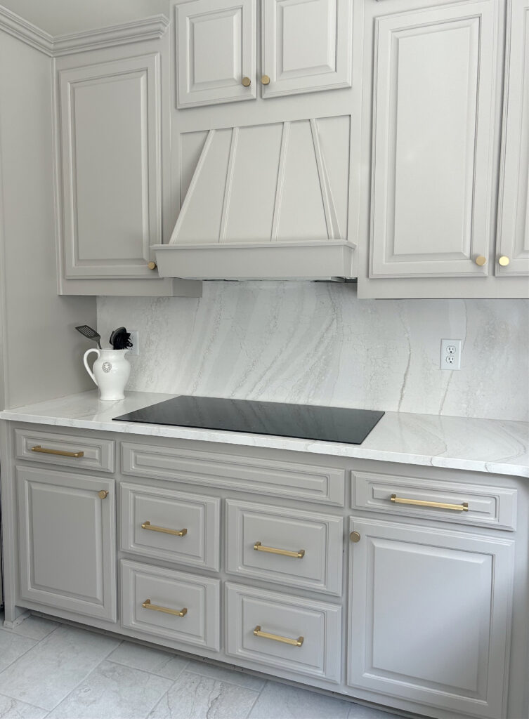 Cambria Everleigh warm gray taupe painted cabinets, Benjamin Moore, countersplash countertop on backsplash, gold hardware, induction range, taupe greige, warm gray floor tile