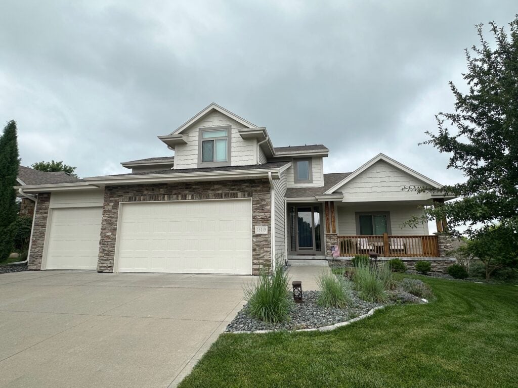 Exterior with neutral stone, Benjamin Moore Edgecomb Gray painted siding, Elephant Ear Sherwin Williams trim with taupe tan windows, wood beam and railing, asphalt roof