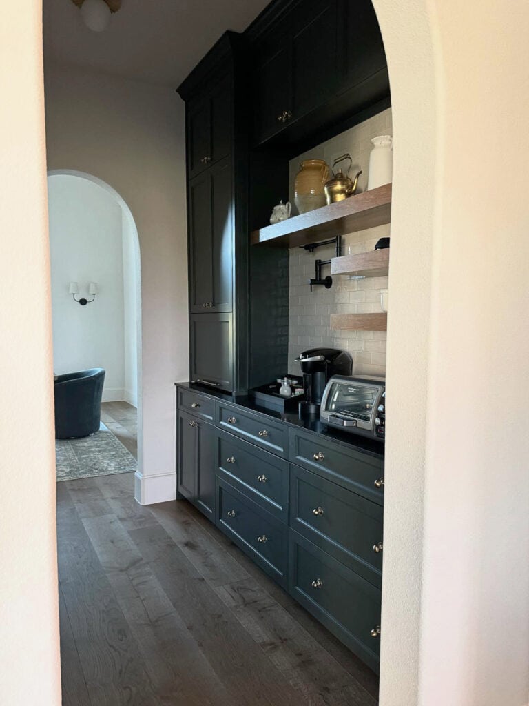 Sherwin Williams Rock bottom dark blue-green teal painted walk in pantry, butler's cabinets, Black quartz countertop, dark wood floor, subway tile, floating wood shelves