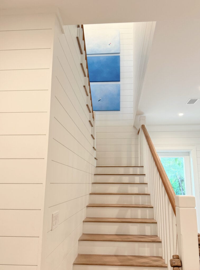Staircase, wood treads and railing, white risers and wood spindles, soft white shiplap painted Sherwin Williams Snowbound,