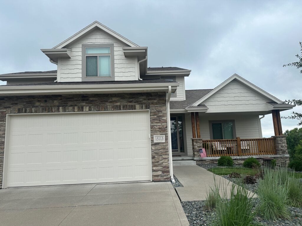 exterior after painting, stone facade, beige brown, gray, asphalt roof, Benjamin Moore Edgecomb Gray siding, greige trim, taupe almond windows, wood beam and railing, garage door. Elephant Ear