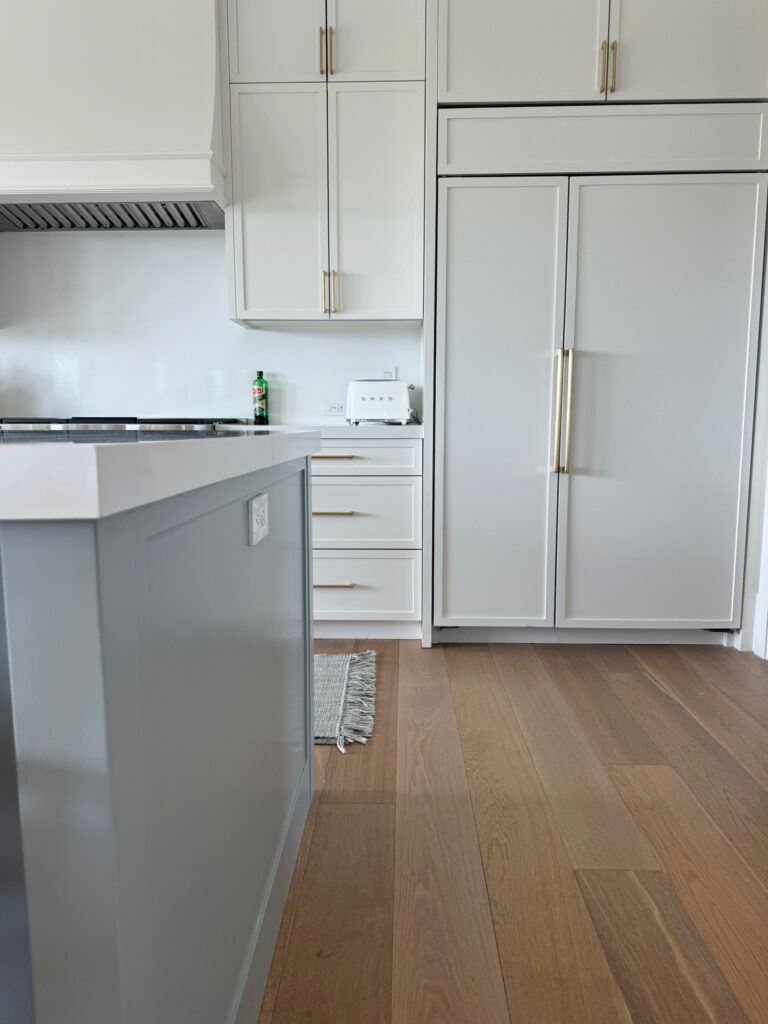 kitchen island painted Boothbay Gray, Benjamin Moore, home of LeMel jewelry, wood floor, Snowbound painted cabinets, white quartz and countersplash