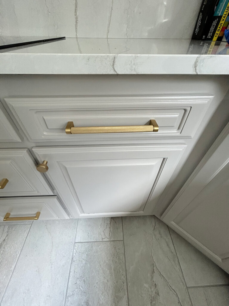 taupe greige tile floor, Cambria Everleigh quartz countertop, Benjamin Moore painted wood cabinets, gold hardware