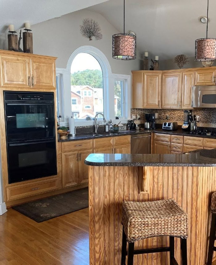 BEFORE KITCHEN WITH raised island, dark granite countertop, maple wood cabinets