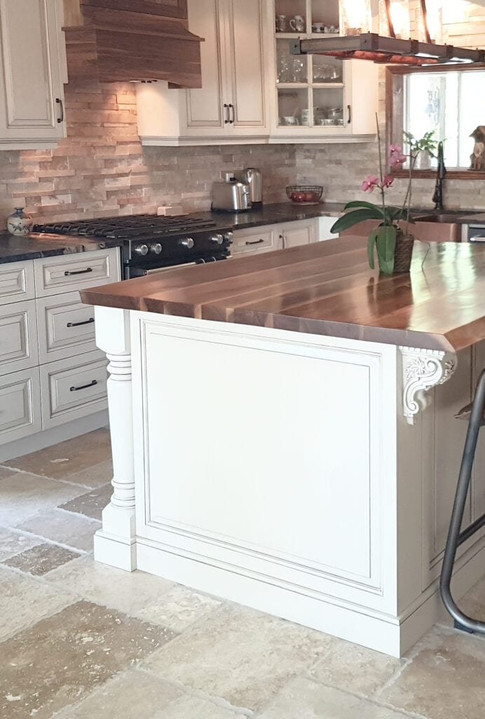 Benjamin Moore Ballet White cream, glazed paint color on kitchen island with travertine tile floor, butcher block wood island.