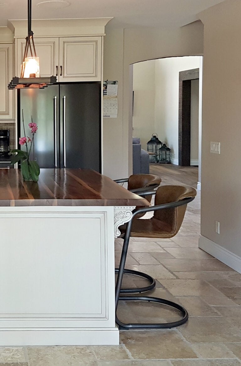 Benjamin Moore Ballet White painted kitchen island with glaze, travertine tile floor, butcher block countertop, stools
