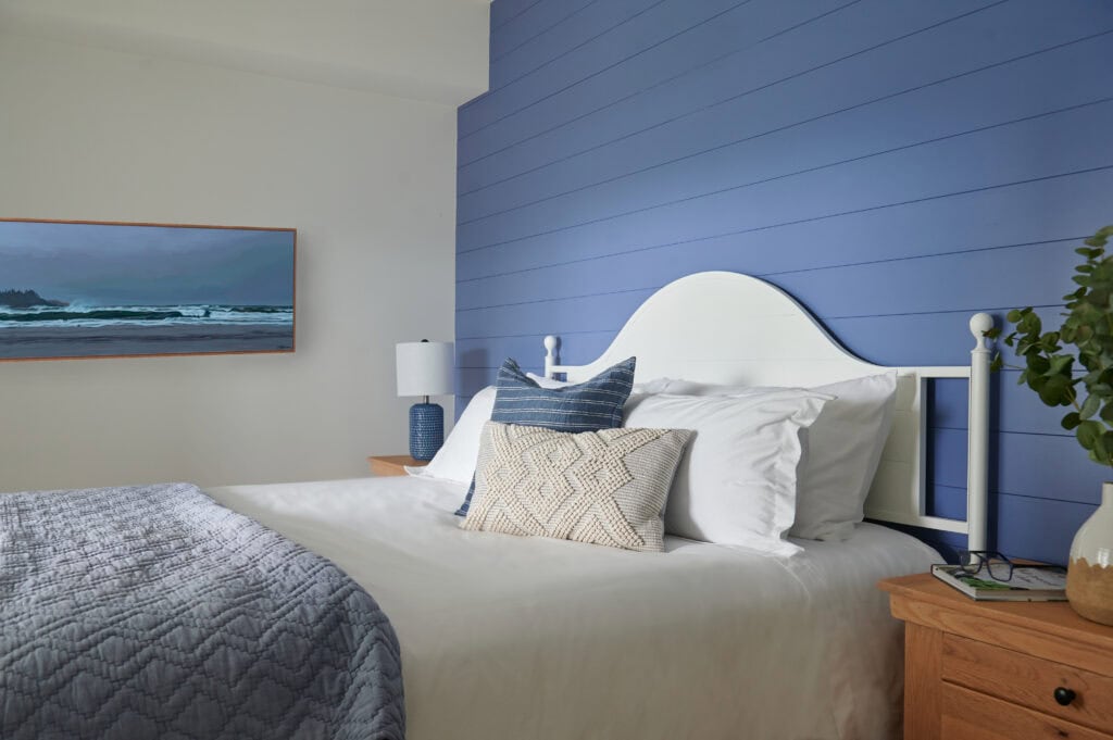 Benjamin Moore Blue Nova acent wall on horizontal shiplap, lake home guest bedroom, white bed linenes, oak side table, and white headboard, Ronei original artwork