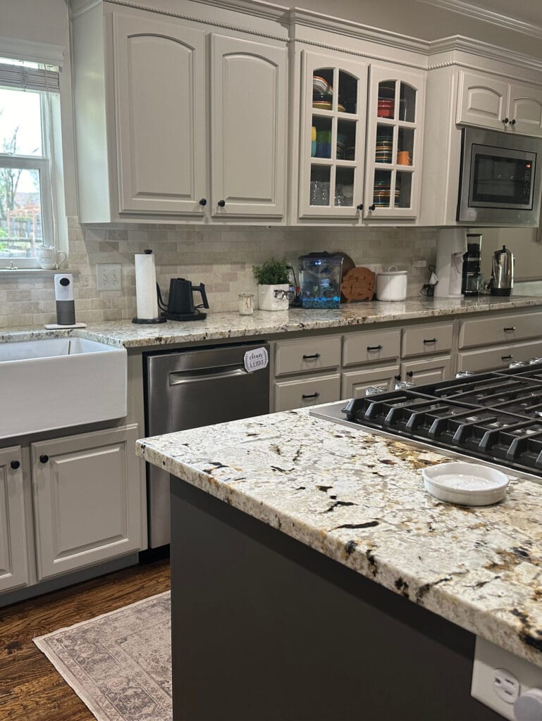 Benjamin Moore Pashmina greige painted wood kitchen cabinets, arched, granite countertop, wood floor, travertine tile backsplash