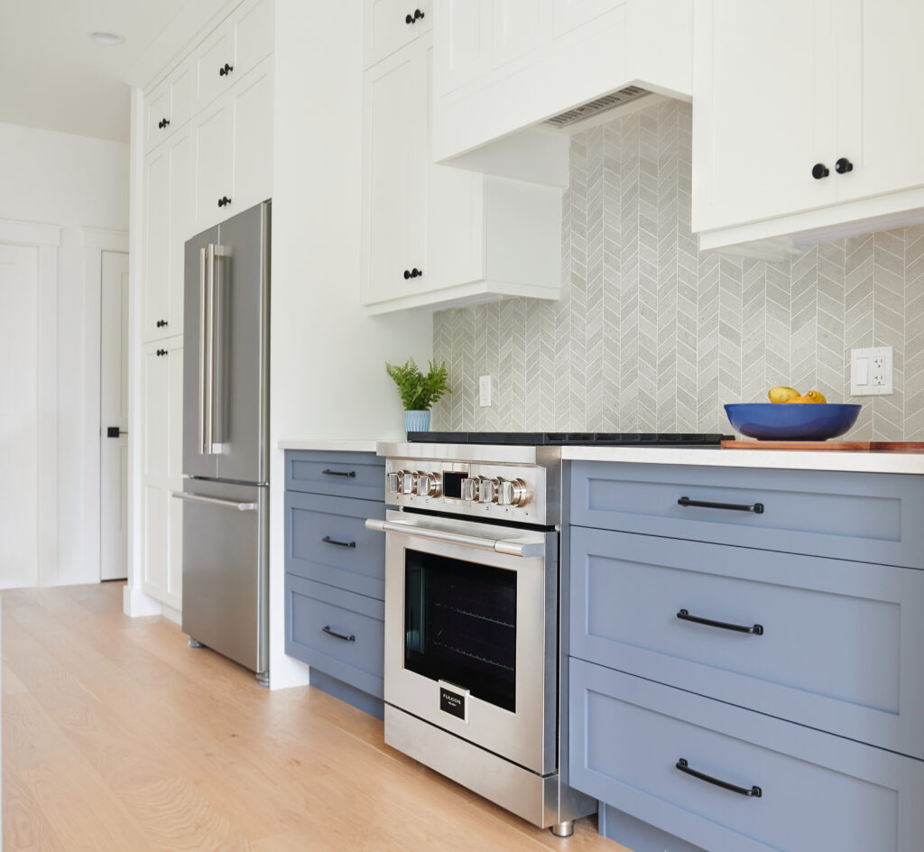 Benjamin Moore White Dove paint color on walls, trims, cabinets, Brittannia Blue lowers and island, fulgor apliances, chevron tile backsplash, white oak flooring