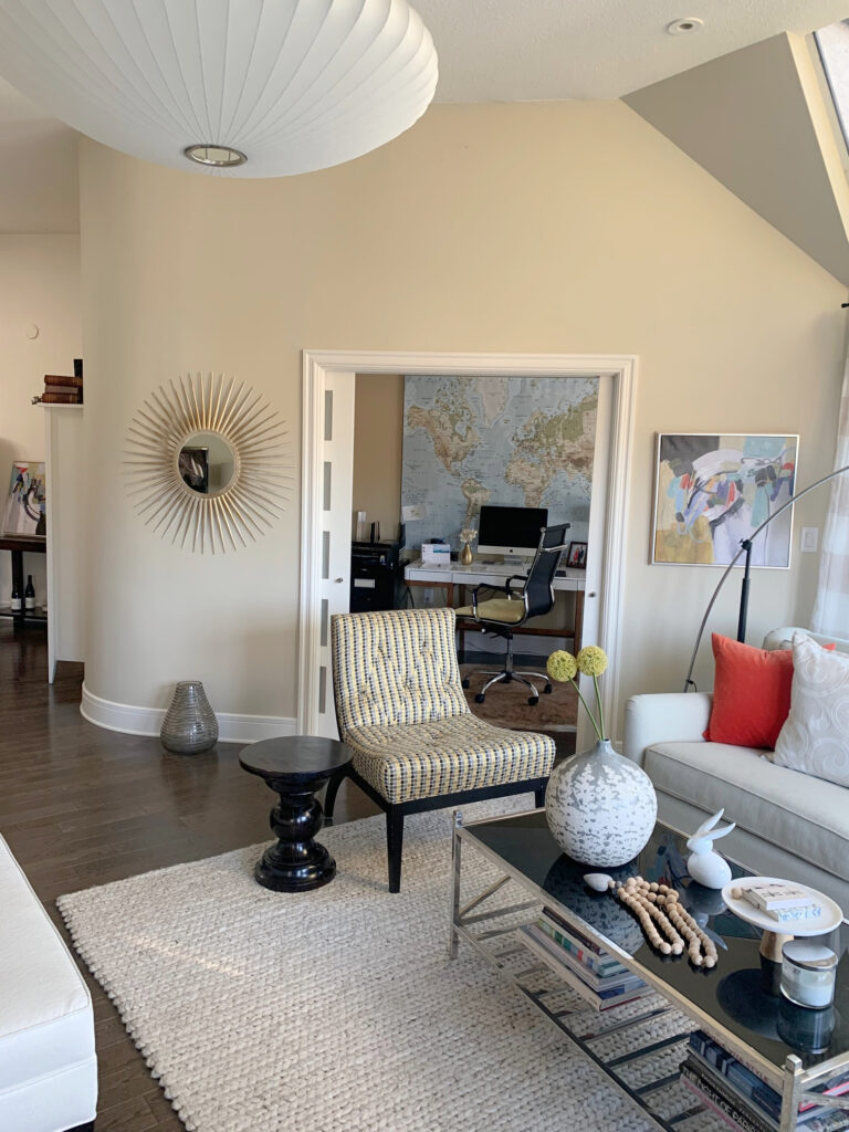Curved wall in family room, Benamin Moore Manchester Tan warm neutral paint color on walls, dark wood floor, eclectic home decor and furniture