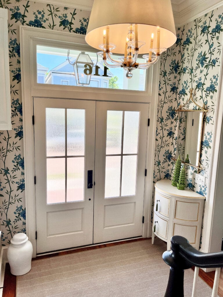 Entryway, white front double door with transom window, white, blue, and green floral wallpaper in foyer.