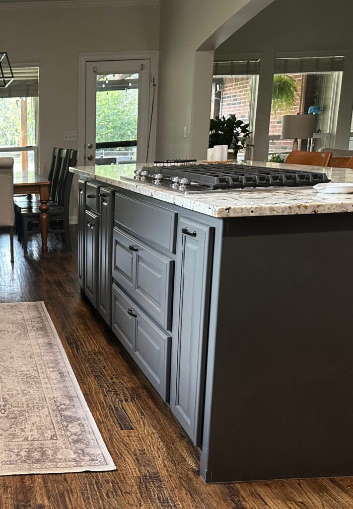 Granite countertop with gold and beige, wood floor, Sherwin Williams Urbane Bronze dark paint color on kitchen island