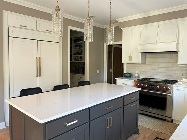 Kitchen painted cabinets, Sherwin Williams Cotton, island Urbane Bronze, white quartz, off-white taupe greige subway tile, Benjamin Moore Pashmina walls, wood floor, gold hardware