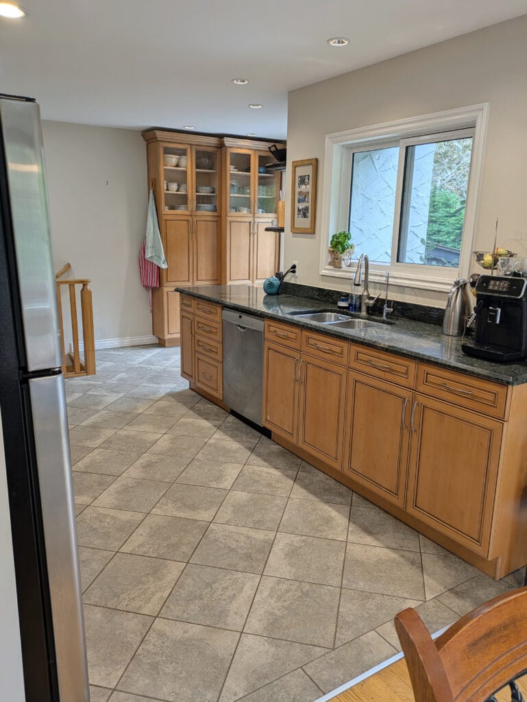 Kitchen with maple orange pink wood cabinets, green granite countertop, beige tile floor, Benjamin Moore Maritime White on walls