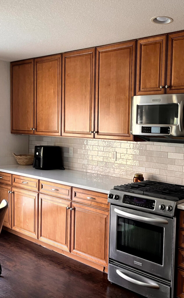 Maple red stained wood cabinets, white quartz, zellige look tile backsplash, White Dove walls, stainless steel appliances, cherry wood floor, dark