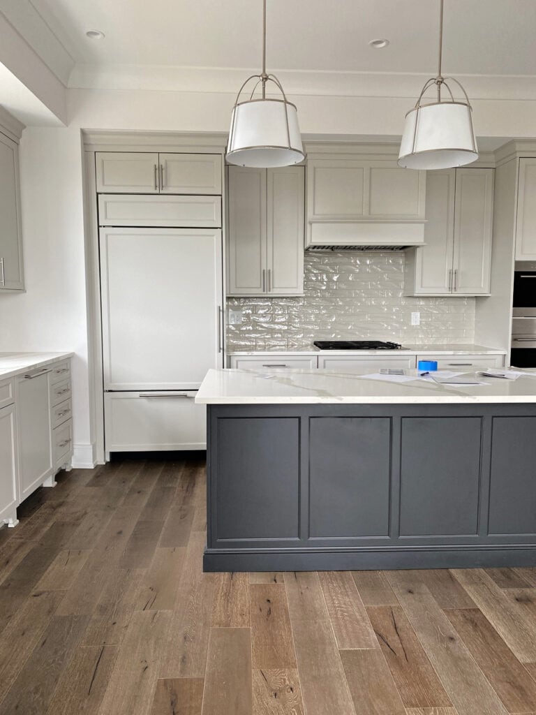 Sherwin Williams Agreeable Gray painted greige cabinets, Snowbound paint color on walls, Iron Ore black island. White quartz countertop, subway tile, wood floor. Kylie M client photo (1)