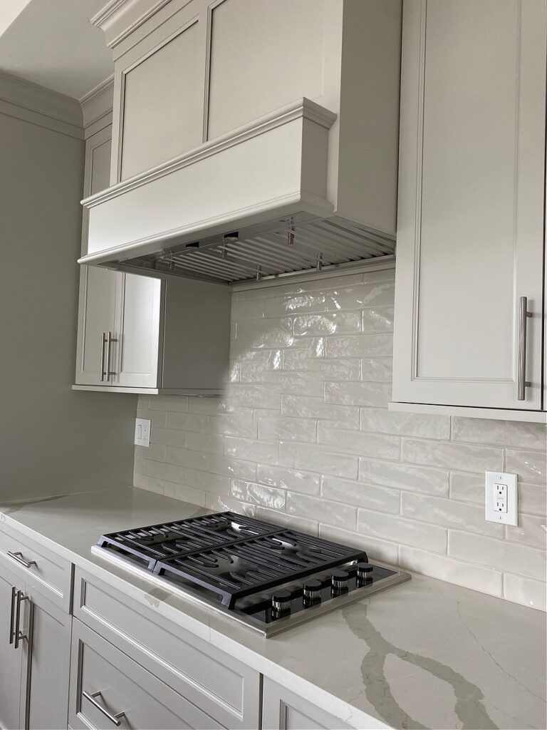 Sherwin Williams Agreeable Gray painted greige warm gray off white cabinets with subway tile backsplash and quartz countertop