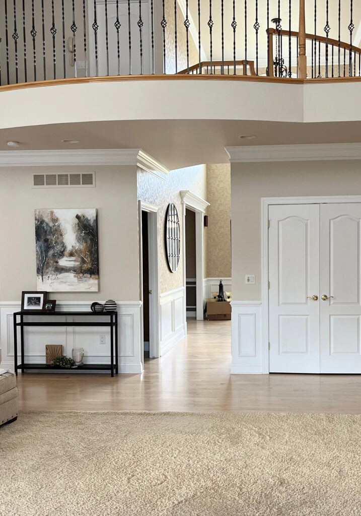 Sherwin Williams Natural Linen beige paint color on walls, Extra White trim and wainscoting, oak and metal spindle railing, light maple floor, 2000s home (1)