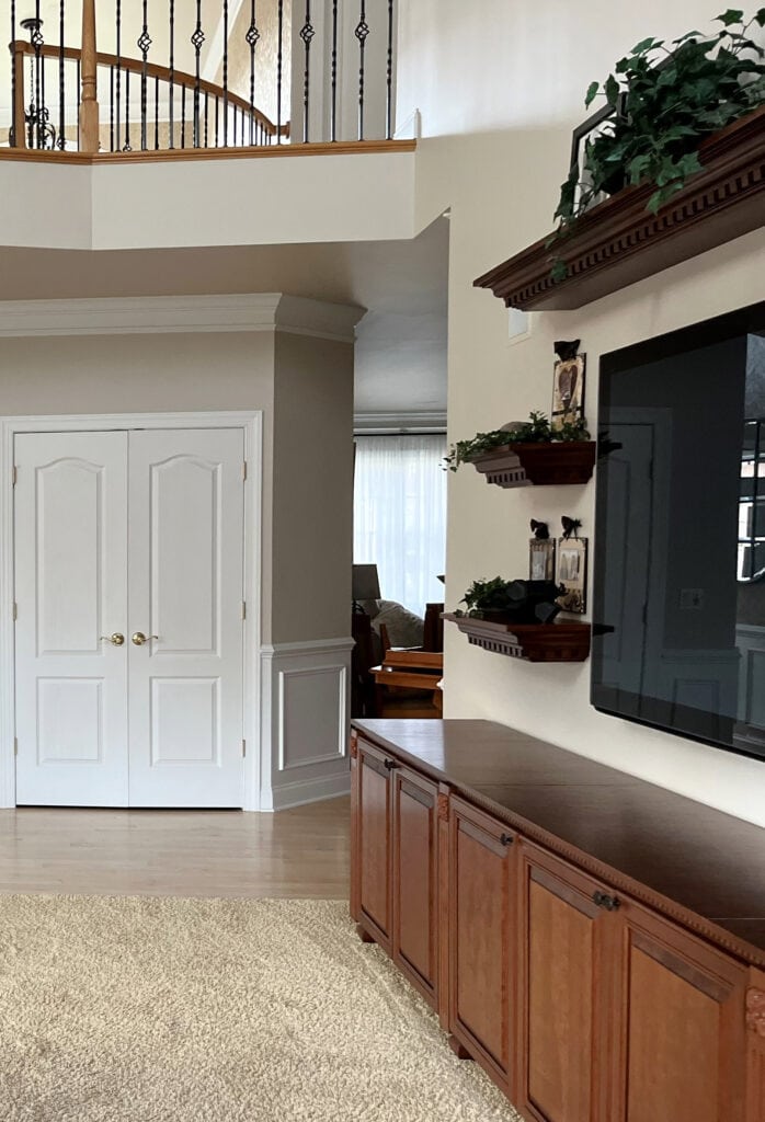 Sherwin Williams Natural Linen beige paint color on walls, Extra White trim and wainscoting, oak and metal spindle railing, light maple floor, 2000s home