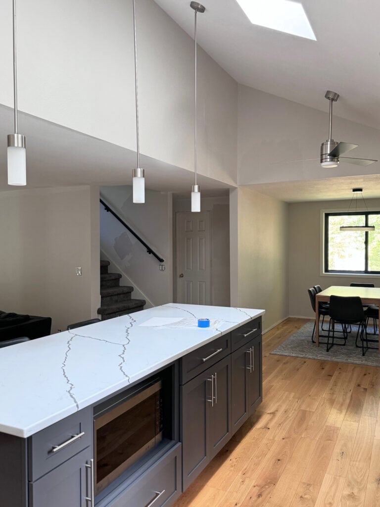 Sherwin Williams Peppercorn painted kitchen cabinets, wood floor, white quartz countertop with veining, Egret White 25 darker on walls