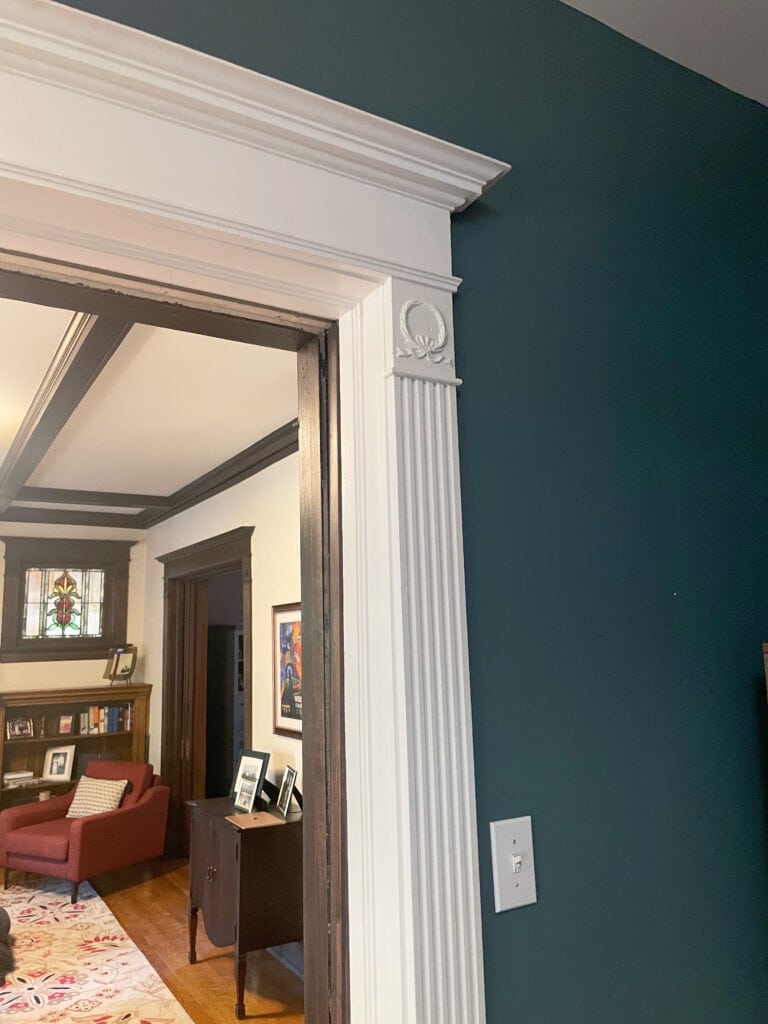 Sherwin Williams Riverway blue-green paint color white trim, living room in Creamy with dark wood trim and built-ins