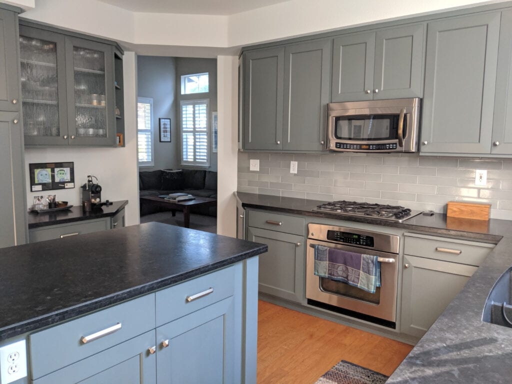Wood floor in kitchen with green-gray subway tile backsplash, honed black granite or soapstone countertop and island, Benjamin Moore Kitty Gray lightened cabinets