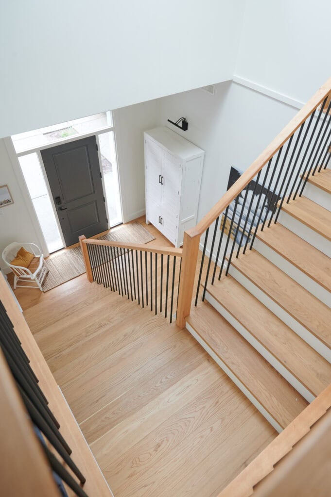 benjamin moore white dove paint color in staircase with white oak treads, white risers, black metal spindles, hemlock wood hand railing, Tricorn Black front door