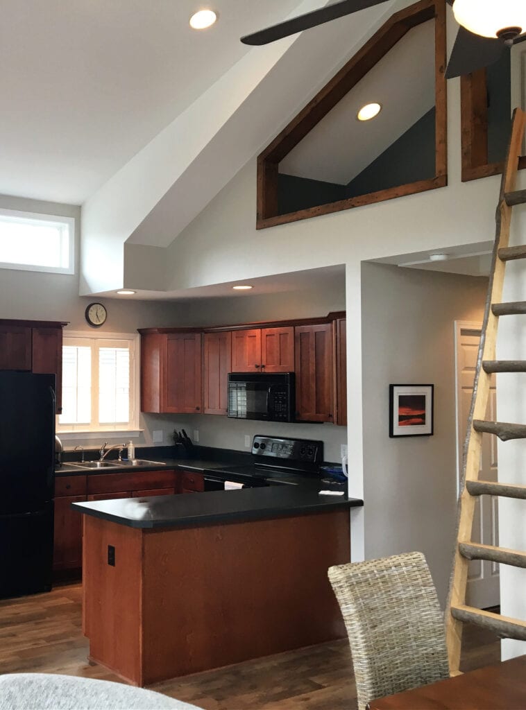 cherry red maple wood kitchen cabinets, black granite countertop, loft, air b and b with Sherwin Williams Worldly Gray, greige paint color on walls