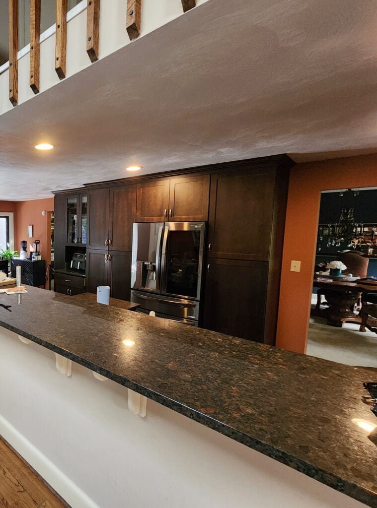 dark wood kitchen cabinets, granite countertop, brown oak floor, rust orange wall color