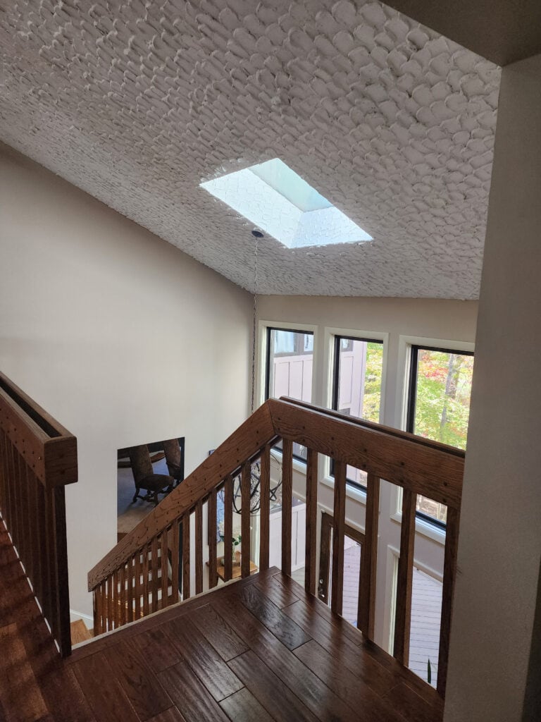 heavily textured ceiling in 1970 or 1980 home with wood hand railing on stairs