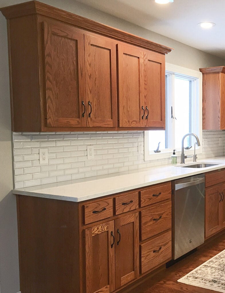 red oak wood kitchen cabinets, white quartz countertops with subway tile update ideas, wood floor and stainless appliances