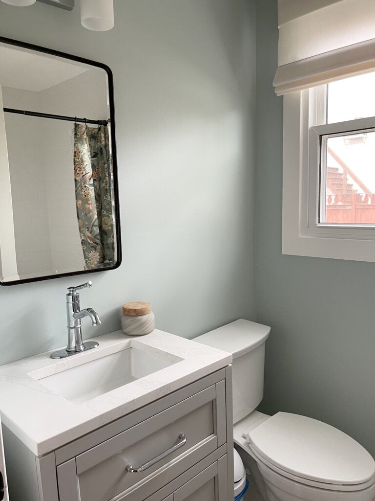 small bathroom or powder room, light gray single sink vanity, Sherwin Williams Rainwashed paint color blue green walls with White Dove lightened trim. north facing
