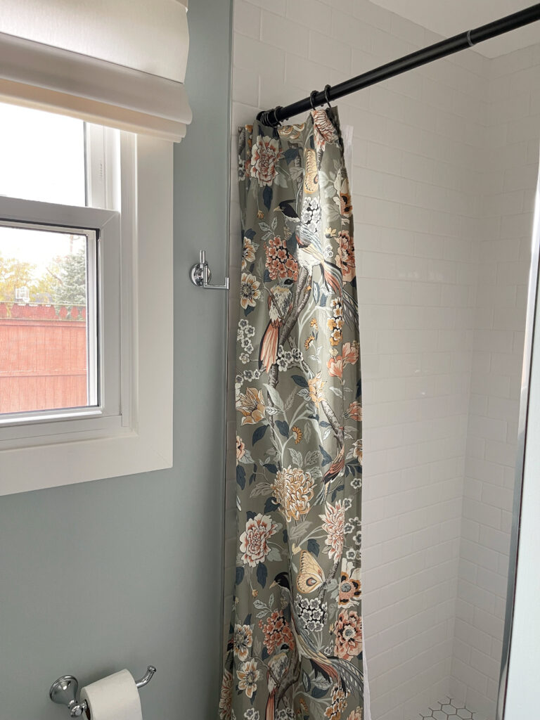 small bathroom with walk in shower, white subway tile, Sherwin Williams RAinwashed paint color on walls, lightened White Dove trim, patterned shower curtain. north facing