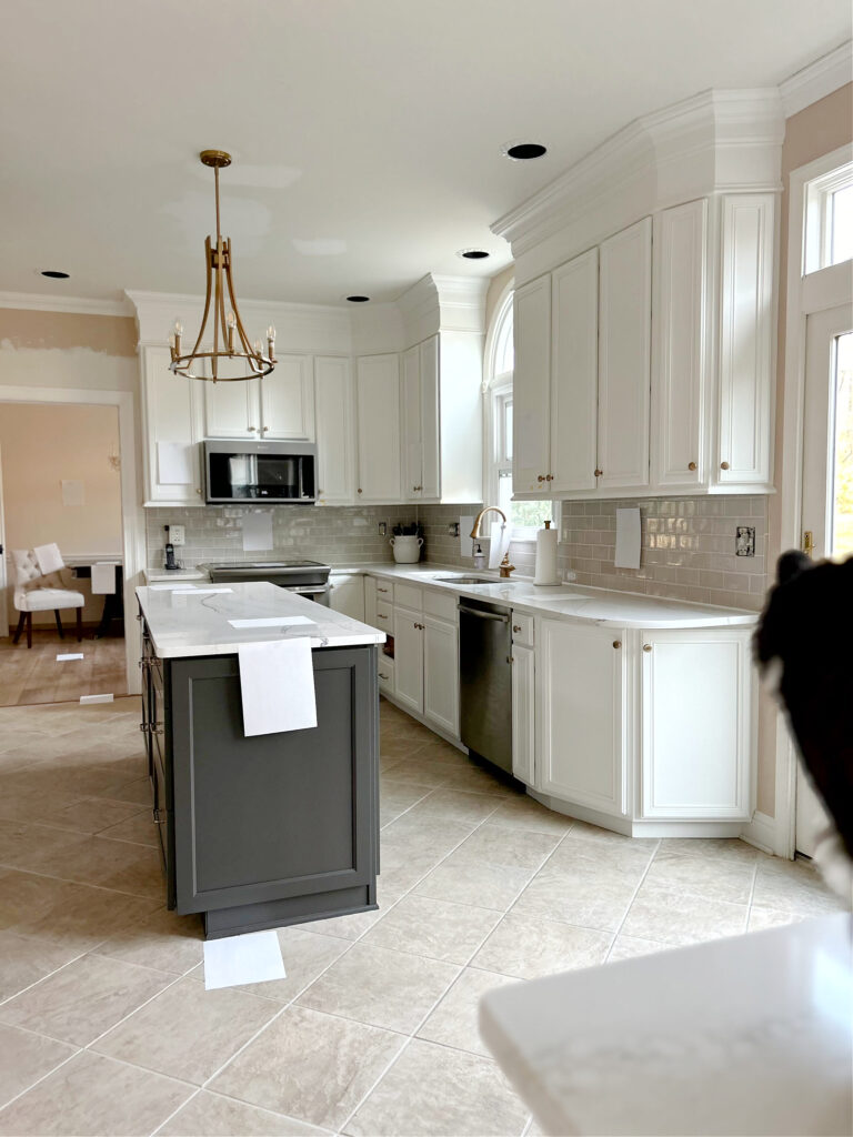 subway tile backsplash, highland park portico pearl, Cambria Lakedale white quartz countertop, Urbane Bronze island, Pure White cabinets, gold hardware, beige tile floor