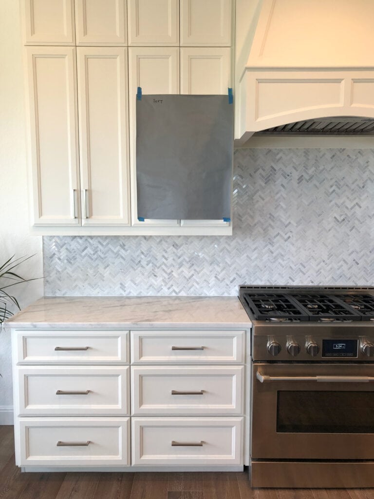 white kitchen cabinets, dark wood floor, Sherwin Williams Software, dark gray cabinet color, marble countertop, marble herringbone backsplash tile