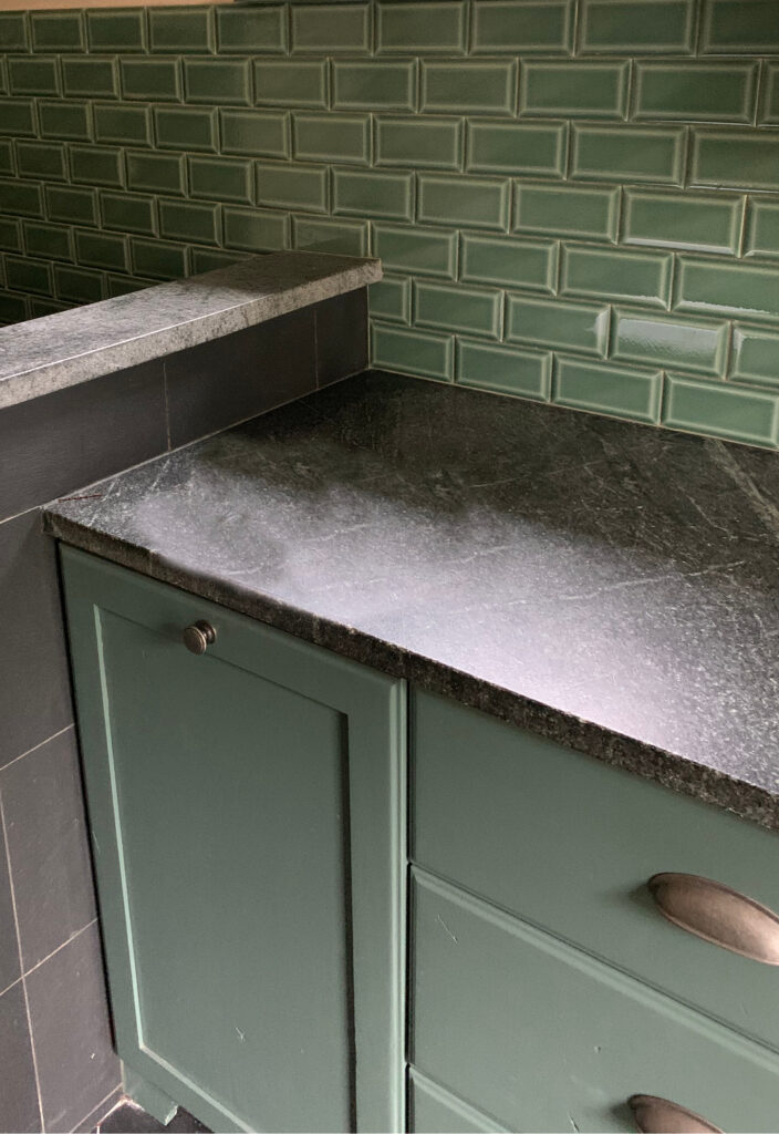 Benjamin Moore Avon Green, dark green painted wood cabinets in laundry room with green subway tile, soapstone countertop and dark gray tile