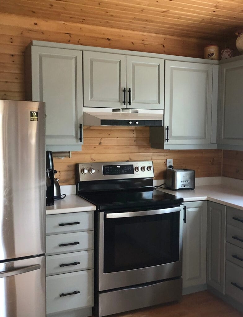 Benjamin Moore Boothbay Gray, gray-blue-green painted wood kitchen cabinets, white countgertop, wood floor, tongue and groove wood walls similar to log home