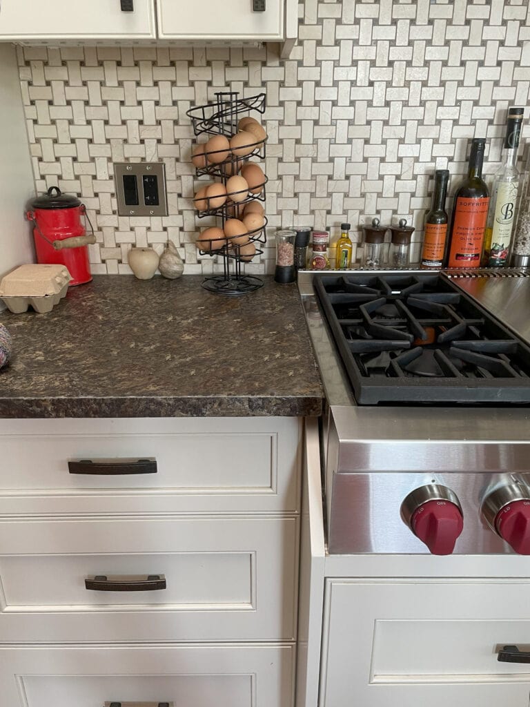 Benjamin Moore Feather Down painted off-white cream cabinets with granite countertop with black and speckles, marble travertine look backsplash tile