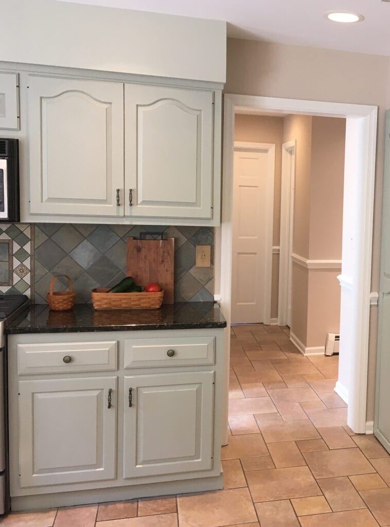 Benjamin Moore October Mist, green painted kitchen cabinets, Cedar Key paint color on walls. Beige and pink toned tile floor in kitchen. dark black granite countertop, 1980 or 1990 kitchen update