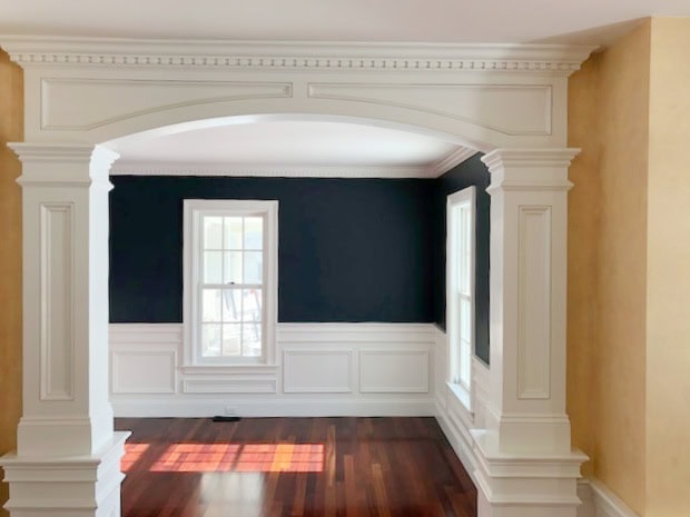 Benjamin moore Hale Navy with arches into dining room, cherry red wood exotic floor, Cloud White moldings and wainscoting