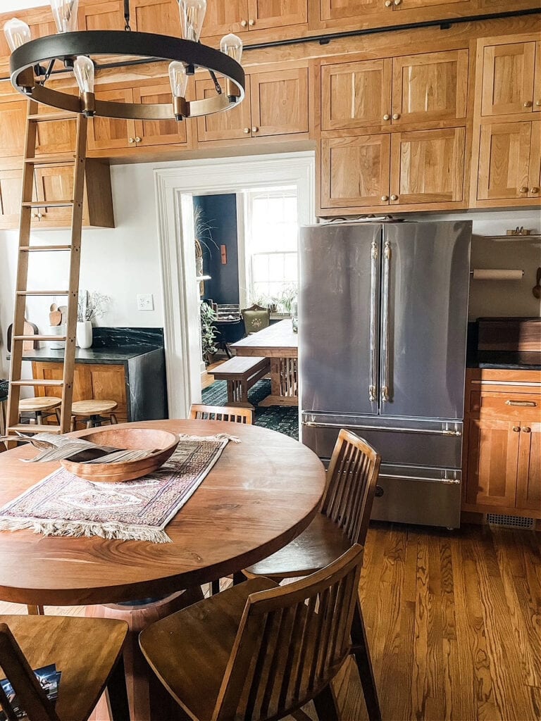 Cherry wood kitchen cabinets, oak floor, rolling library ladder, heritage, stainless steel, black soapstone countertop and backsplash