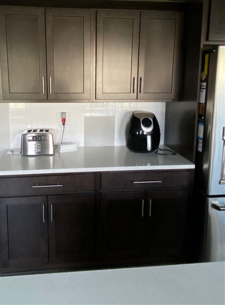 Sherwin Williams Dorian Gray sample with dark wood cabinets and white subway tile backsplash, white quartz